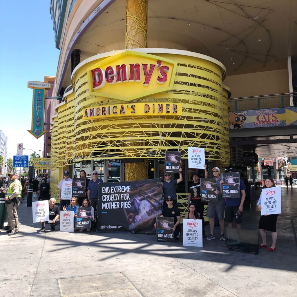 Animal Equality volunteers protesting outside a Denny's restaurant in Las Vegas, with posters and banners.