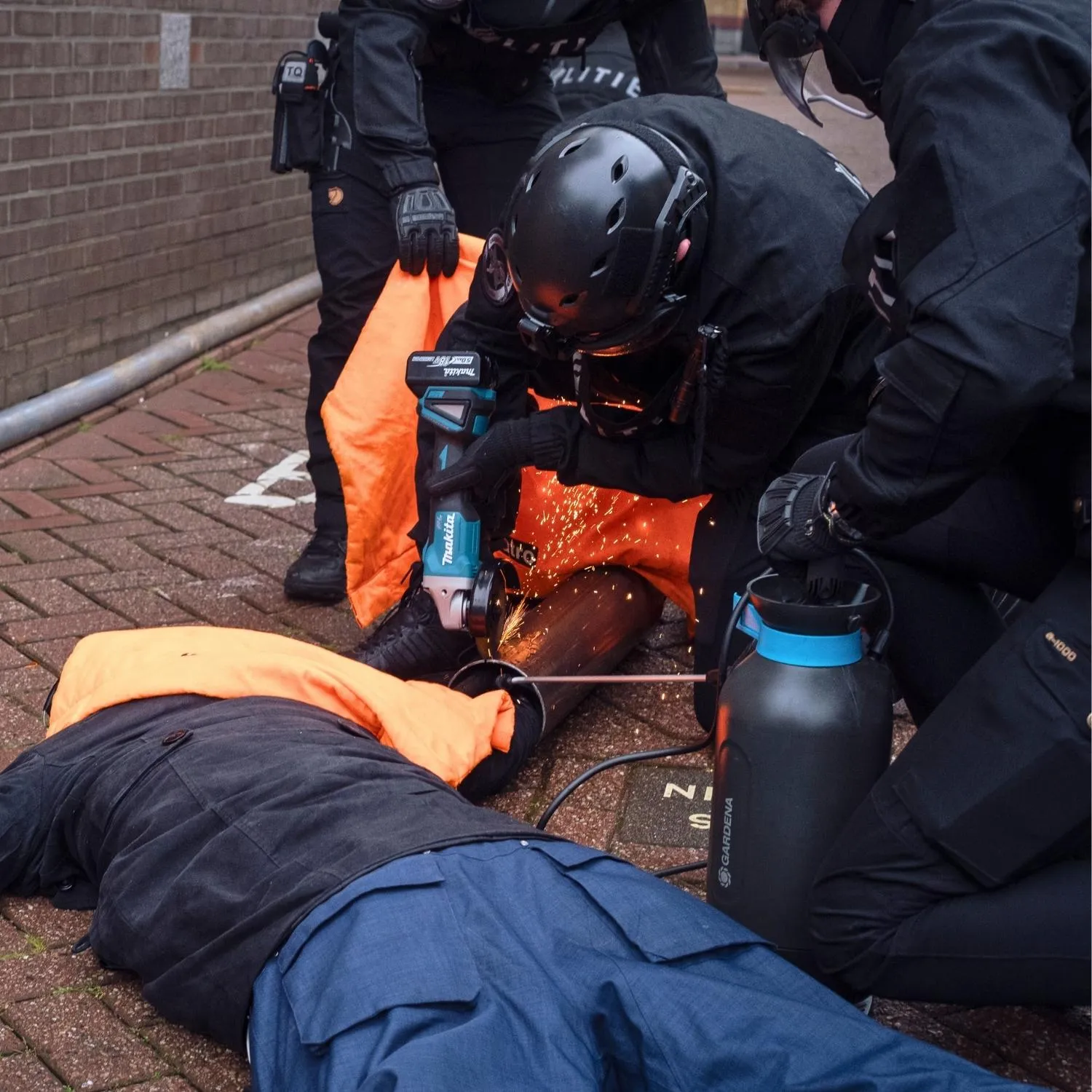 A police officer cuts through chains binding an Animal Equality protester at the Ahold Delhaize headquarters.