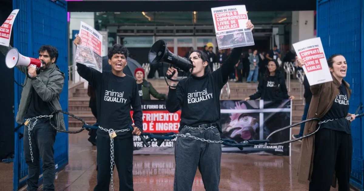Animal Equality activists, chained together, stage a civil disobedience action at APAS Show, confronting McCain Foods representatives over the unfulfilled 2018 cage-free pledge.